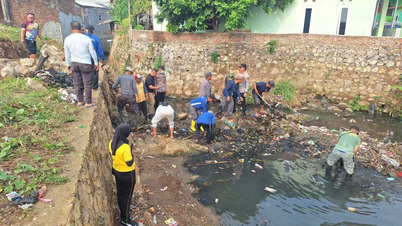 Kapolsek Tanjung Karang Barat AKP Martoyo bersama unsur pemerintah kelurahan dan masyarakat bergotong royong membersihkan aliran sungai di Jalan Sawo 3, Segala Mider, Jumat (30/10/2026).